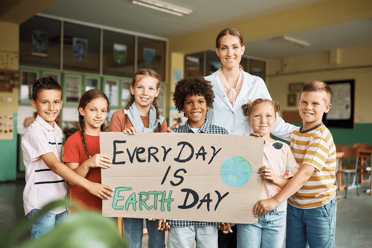 Teacher and students holding up a sign that says 'Every Day is Earth Day'