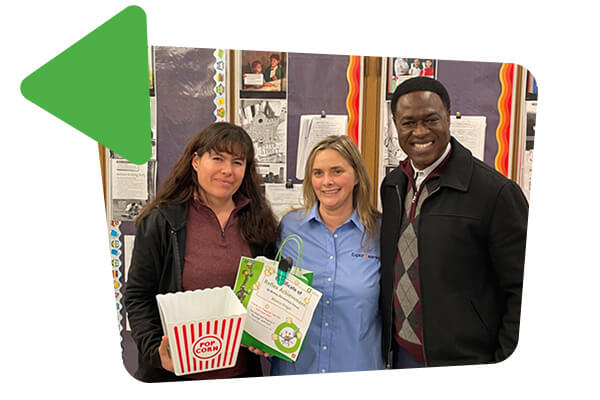 Photo of Olagunju with two other teachers standing in front of a wall with Reflex poster. They are holding popcorn and certificates. They are smiling.